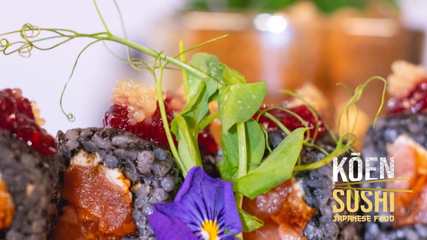 Grande plano de makis de arroz preto com salmão, flor comestível e rebentos, no Koen Sushi